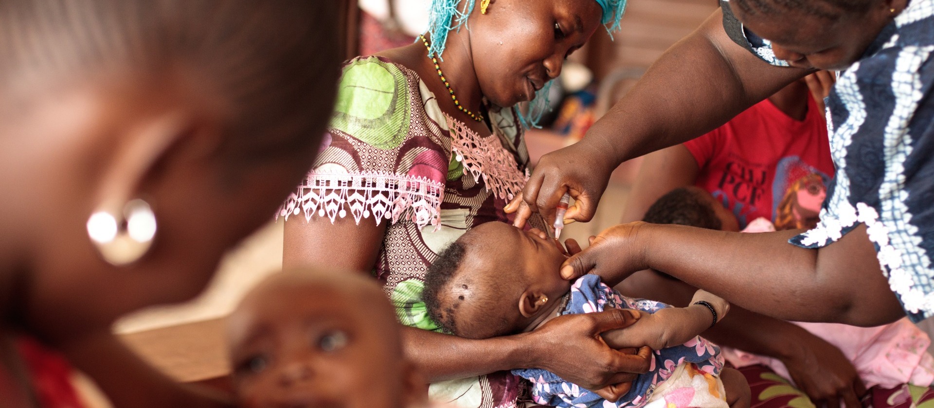 BOOST-Mother-holding-child-receiving-oral-polio-vaccine