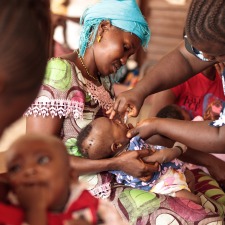 BOOST-Mother-holding-child-receiving-oral-polio-vaccine