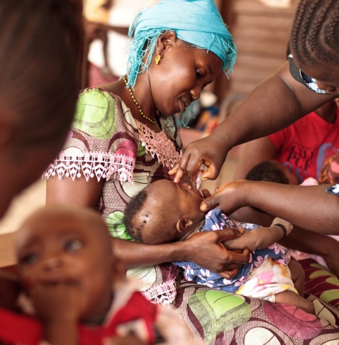 BOOST-Mother-holding-child-receiving-oral-polio-vaccine