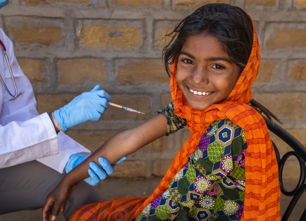 Female caucasian doctor vaccinating young Indian girl in small village, Rajasthan, India
