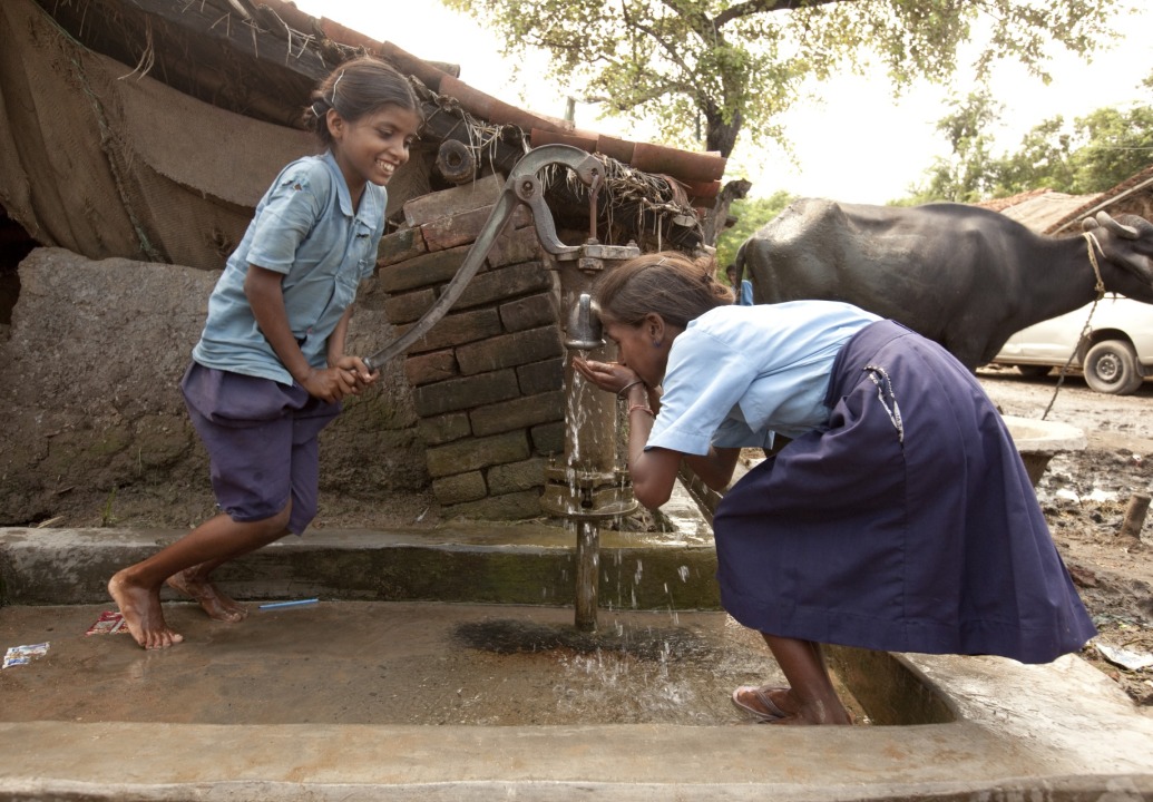 two-children-pump-water-at-well